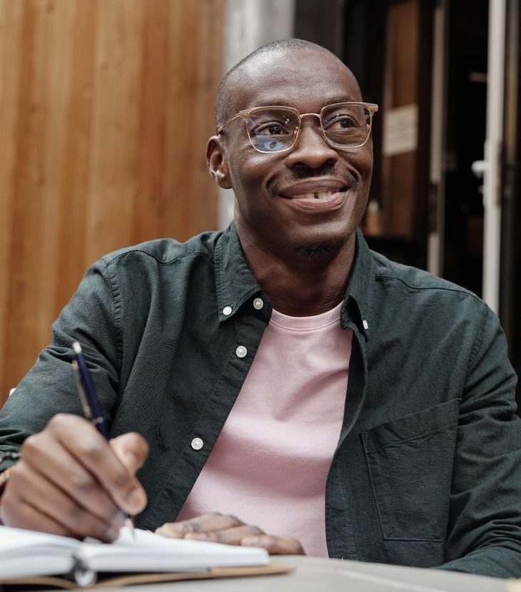 a man wearing eyeglasses holding a pen on a notebook